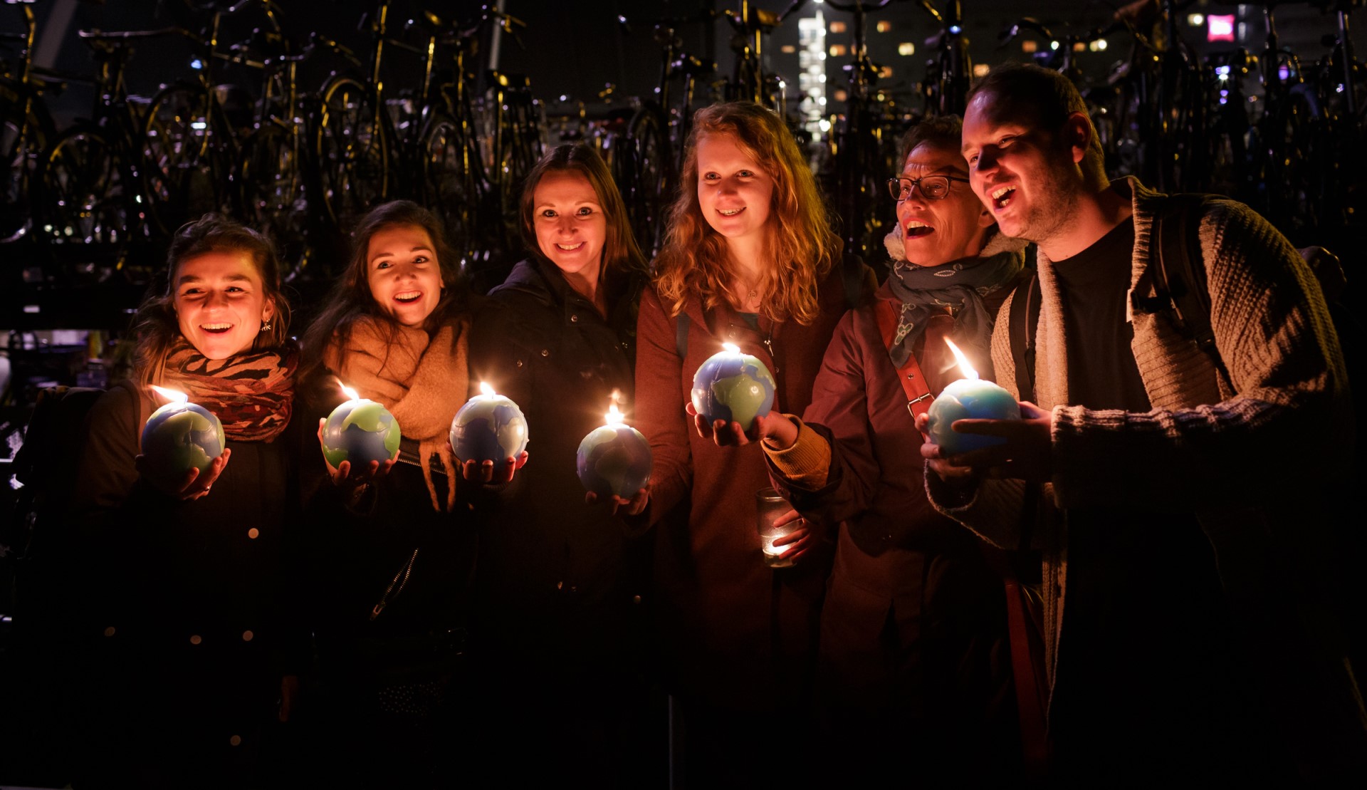 Zes mensen hebben een brandende aardbol kaars vast