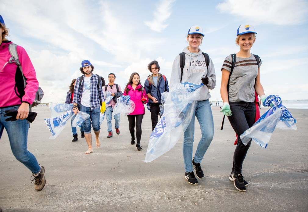 mensen lopen op strand met vuilniszakken